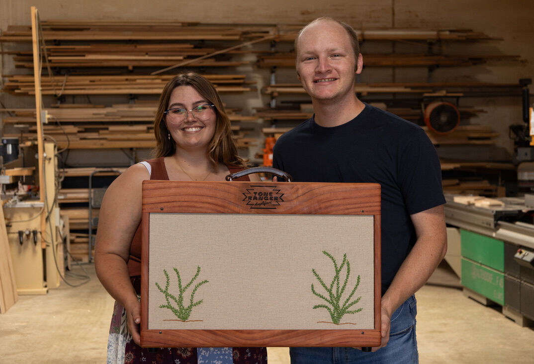 Luke Westrup and Rachel Kent in their shop holding a cactus cabinet