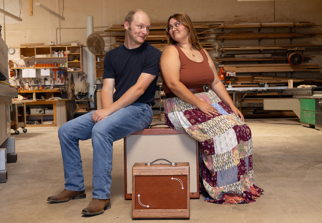 Luke Westrup and Rachel Kent seated in their shop with a cabinet